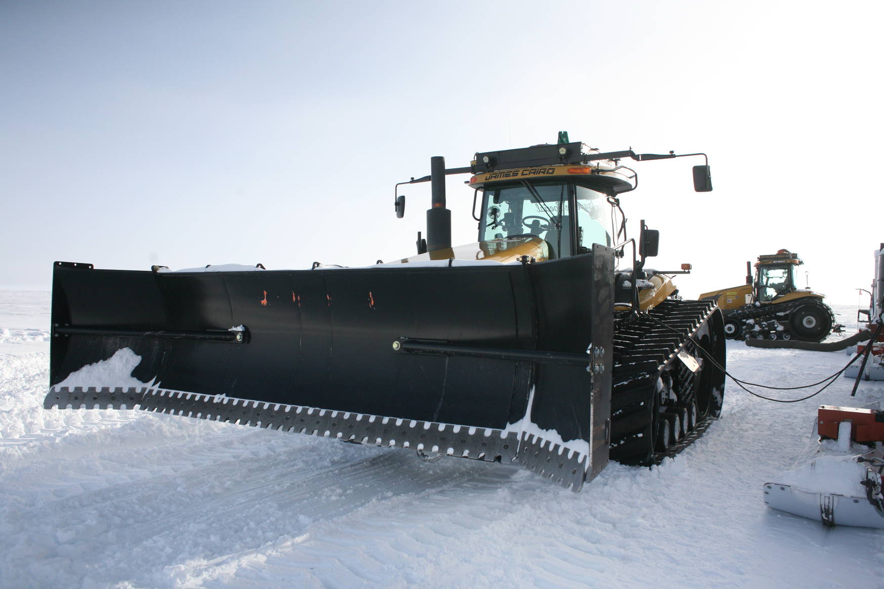 Huge tractors indeed. Here you see one that is equipped with a blade to clear the path of snow drifts.