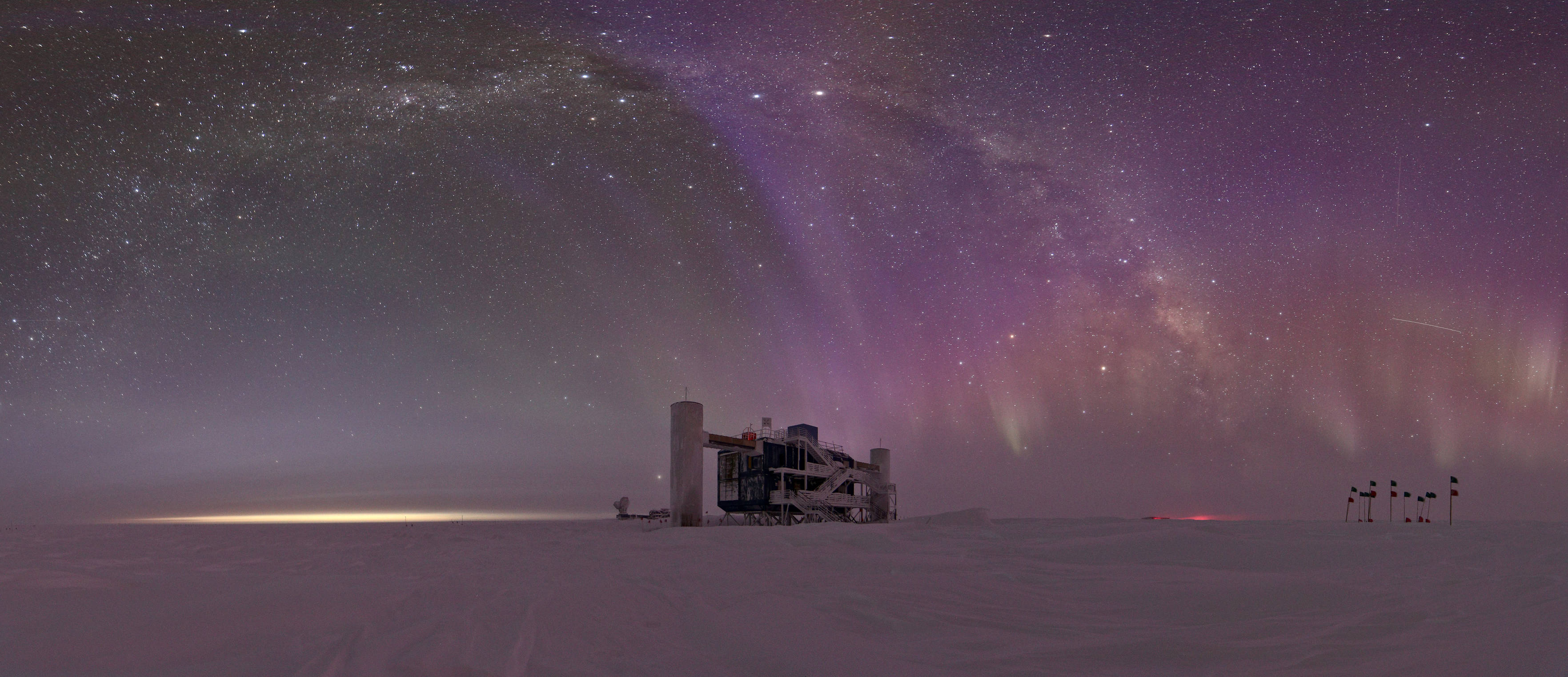 A wide angle shot of the auroras and the Milky Way above the IceCube Laboratory